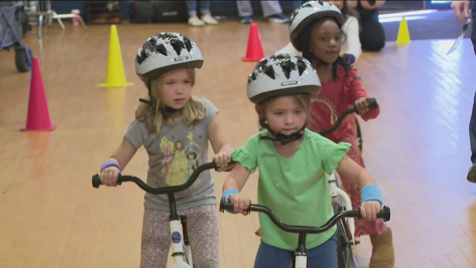 Squeals of delight filled the gym as a giant rainbow parachute lifted to unveil 24 new balance bikes.