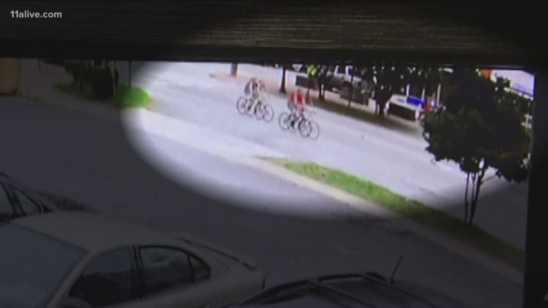 Surveillance video slows the black car following behind them, then suddenly swerving into their lane, hitting the woman and tossing her from her bike.