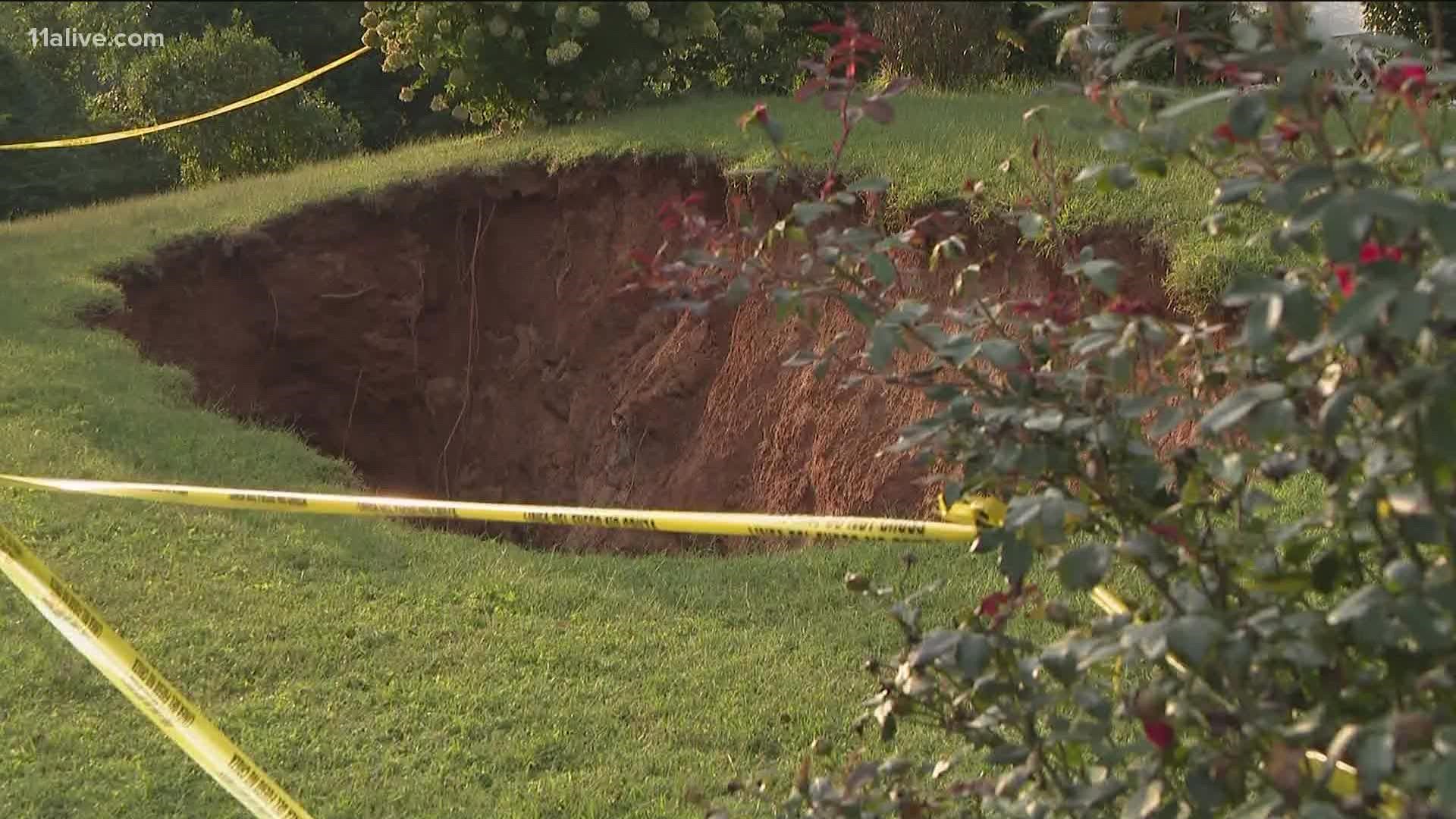 The massive sinkhole is threatening to take over the yard of a Marietta home.