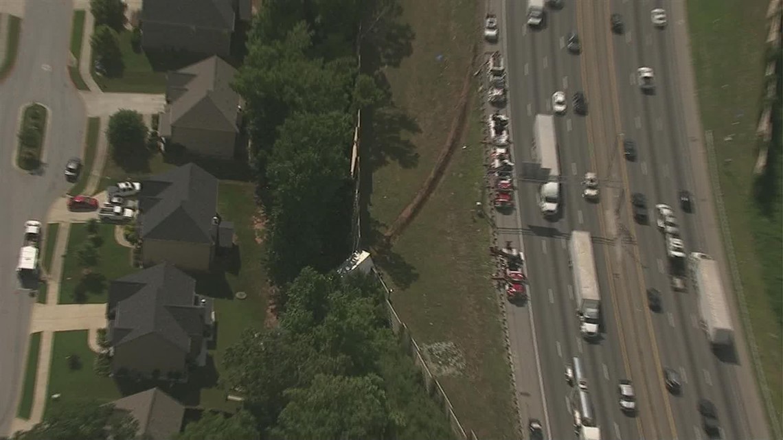 Tractor-trailer veers off I-20, goes through barrier into backyard
