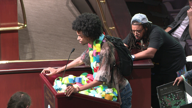 Man with paper chain sings before Atlanta City Council in opposition of police training center