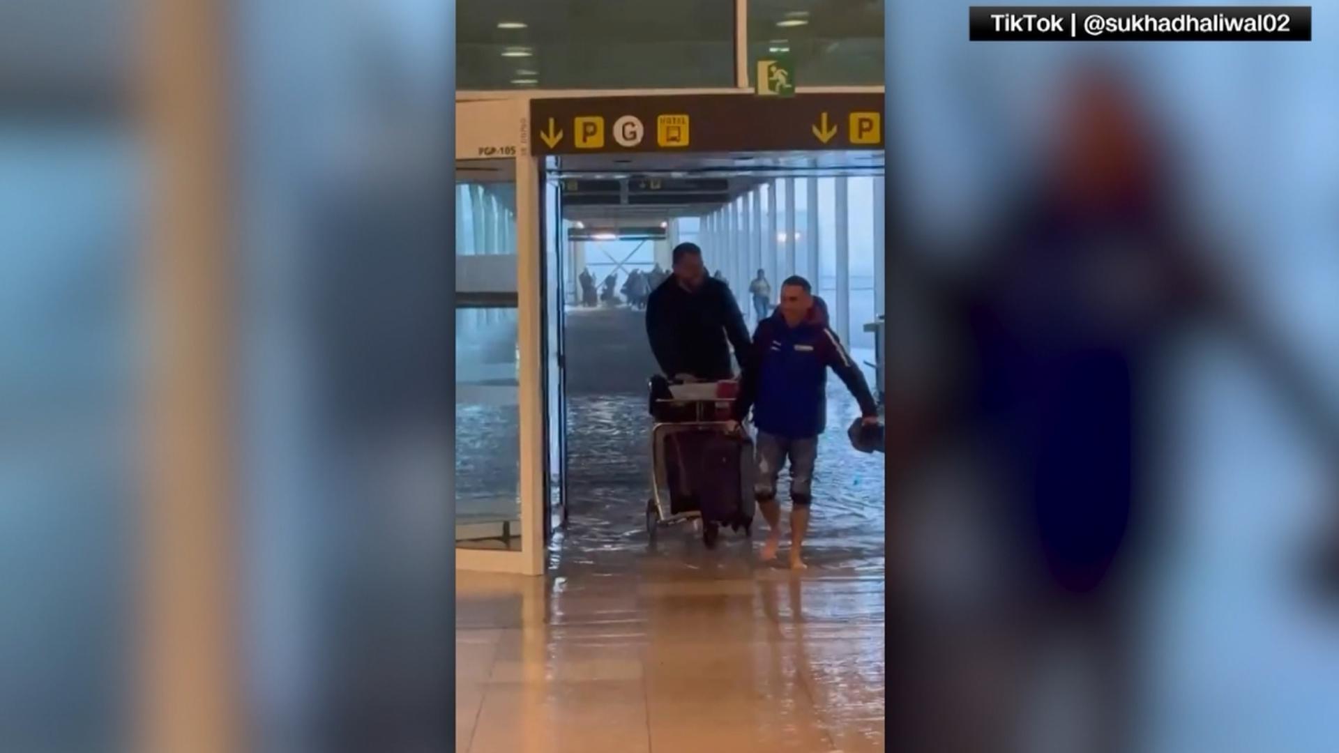 People wade through water inside Barcelona’s flooded airport.